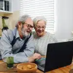 Senior Couple Smiling and Using a Laptop