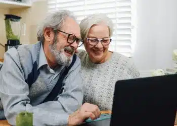 Senior Couple Smiling and Using a Laptop