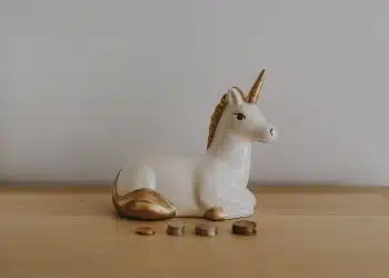 white and gold ceramic unicorn figurine near coins