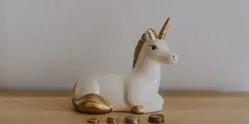 white and gold ceramic unicorn figurine near coins