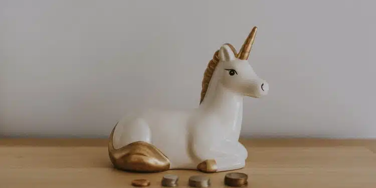 white and gold ceramic unicorn figurine near coins