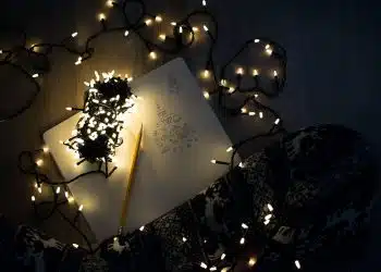 photo of string lights on open book beside pencil