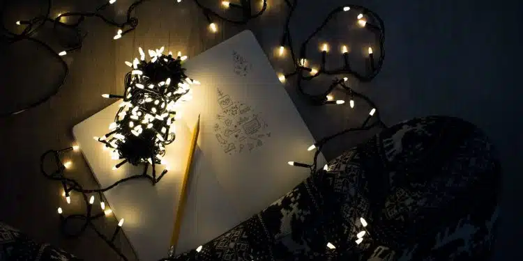 photo of string lights on open book beside pencil